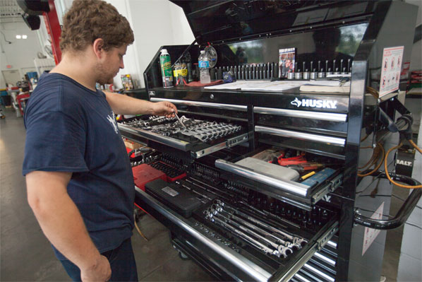 man selecting wrench from tool cabinet