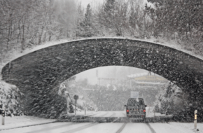 Car driving under a bridge in the snow