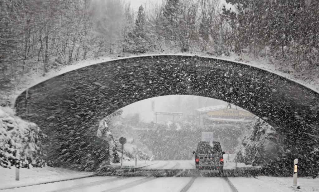 Car driving under a bridge in the snow