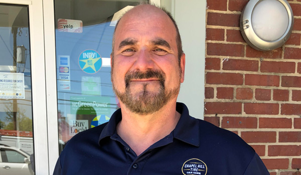 Terry Govoreau smiles. He's wearing a dark blue polo with the Chapel Hill Tire logo.