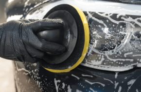 Mechanic washes a vehicle's headlights during an advanced car detailing appointment