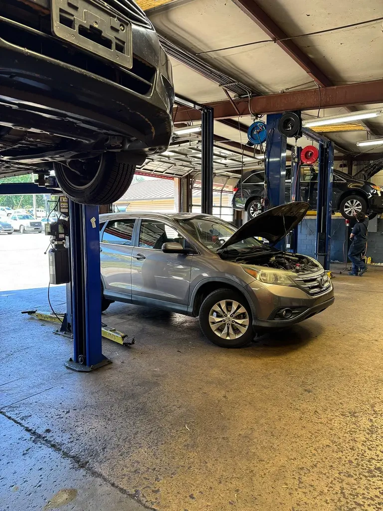 Auto repair shop with SUV hood open and cars lifted
