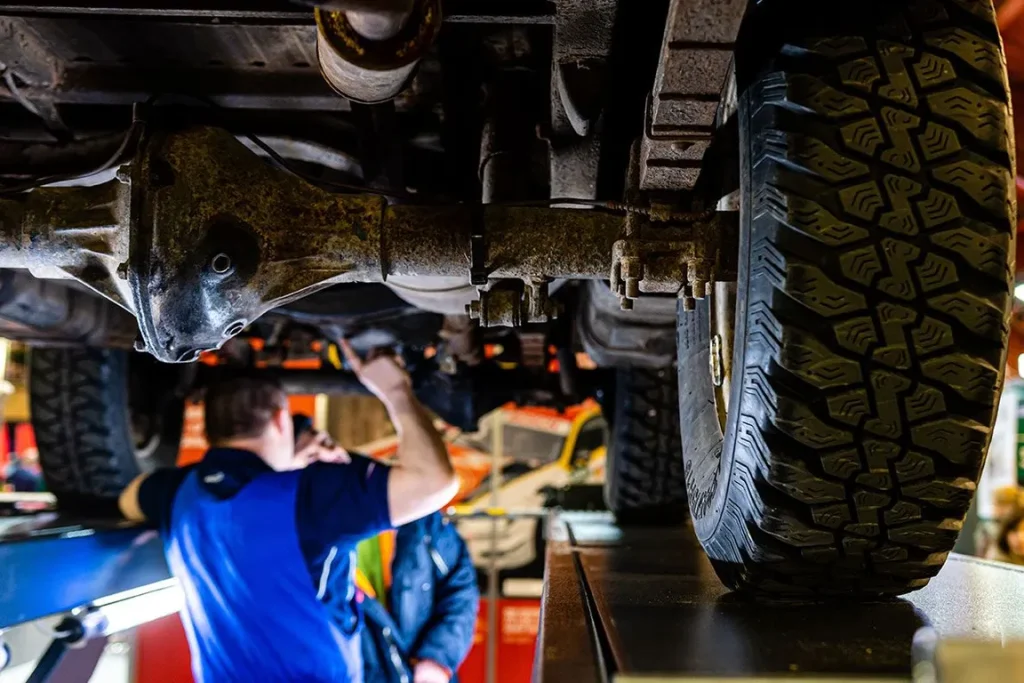 Mechanic inspecting underside of vehicle on lift