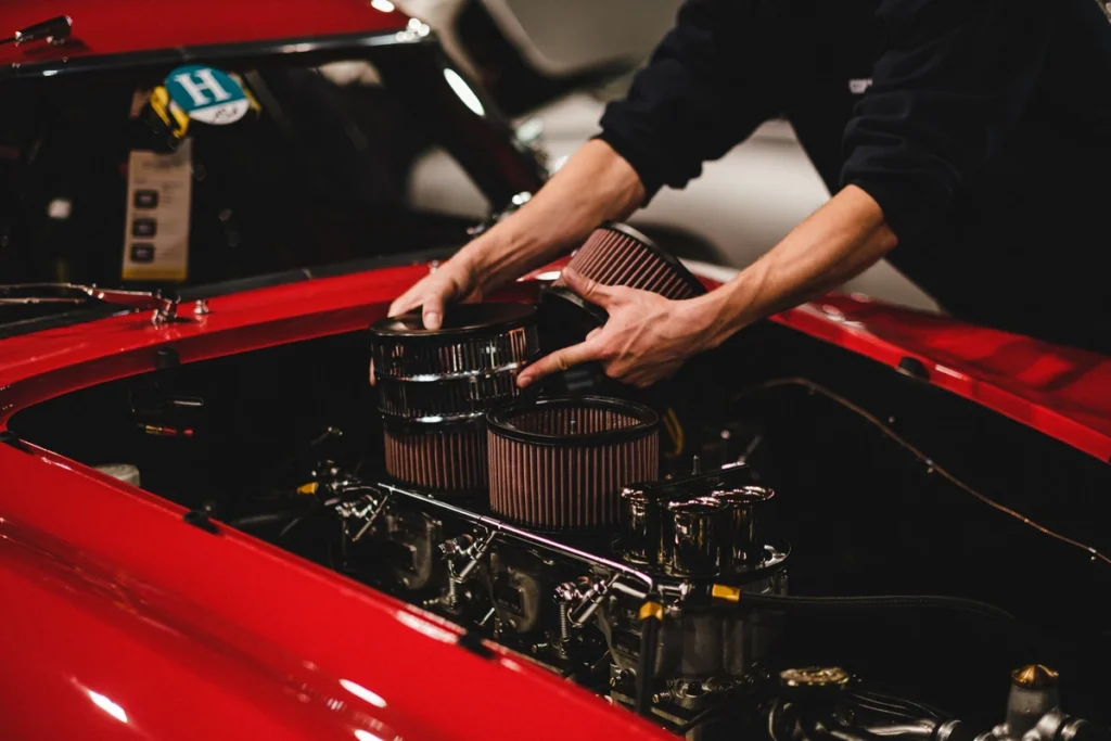 Hands installing air filters on classic car engine