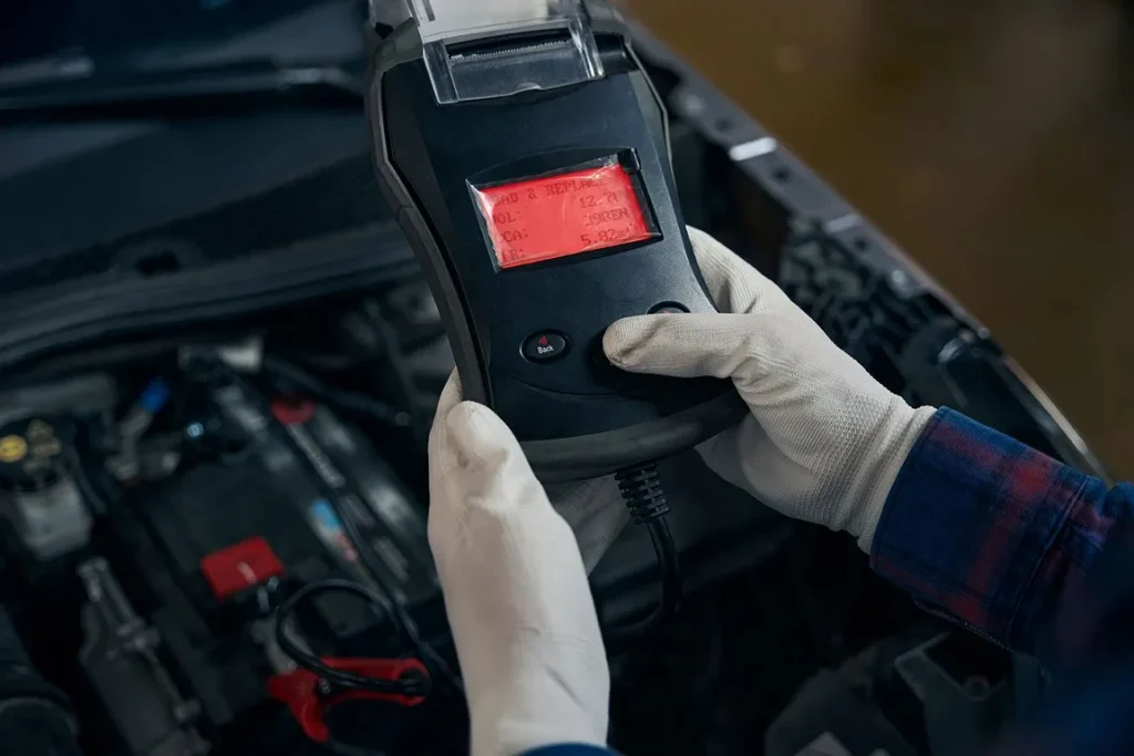 Mechanic using car diagnostic scanner in engine bay