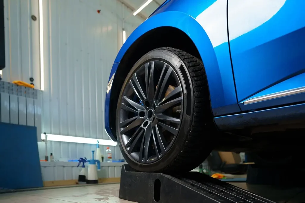 Blue car wheel on service ramp in garage