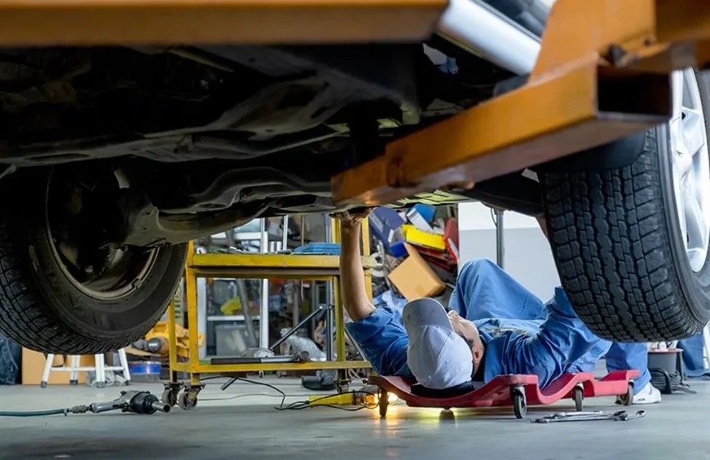 Mechanic working under car in auto repair shop