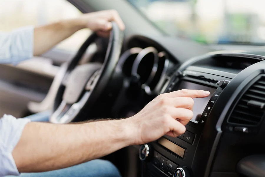 Driver adjusting car touchscreen while holding steering wheel