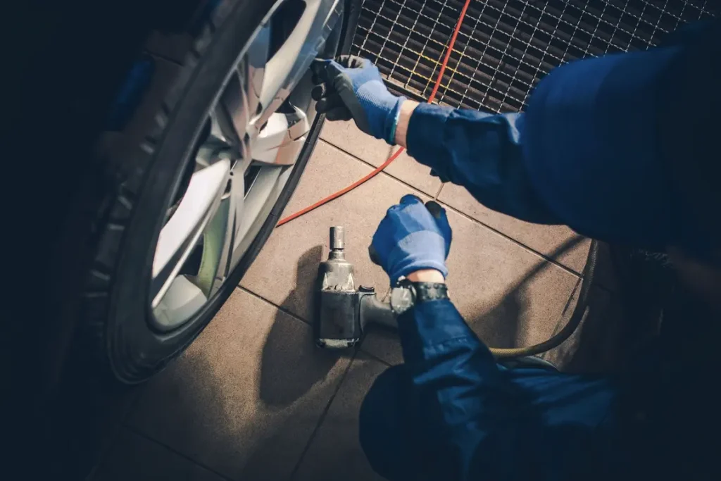 Mechanic using impact wrench on car wheel