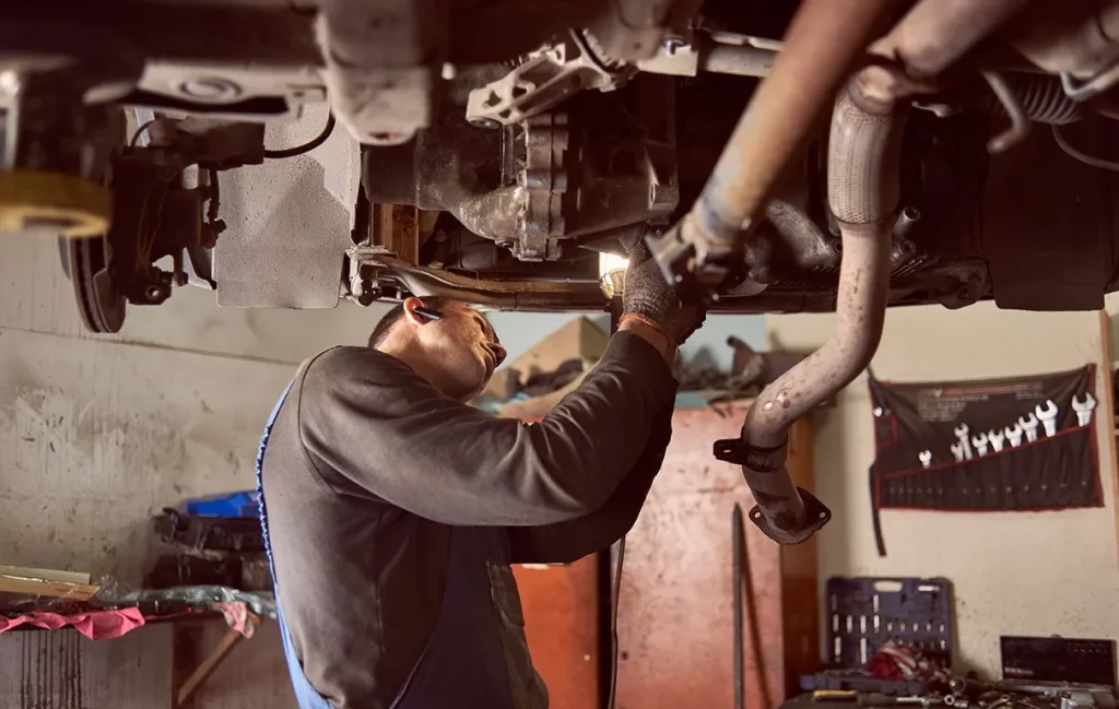 Mechanic repairing car underneath in auto shop
