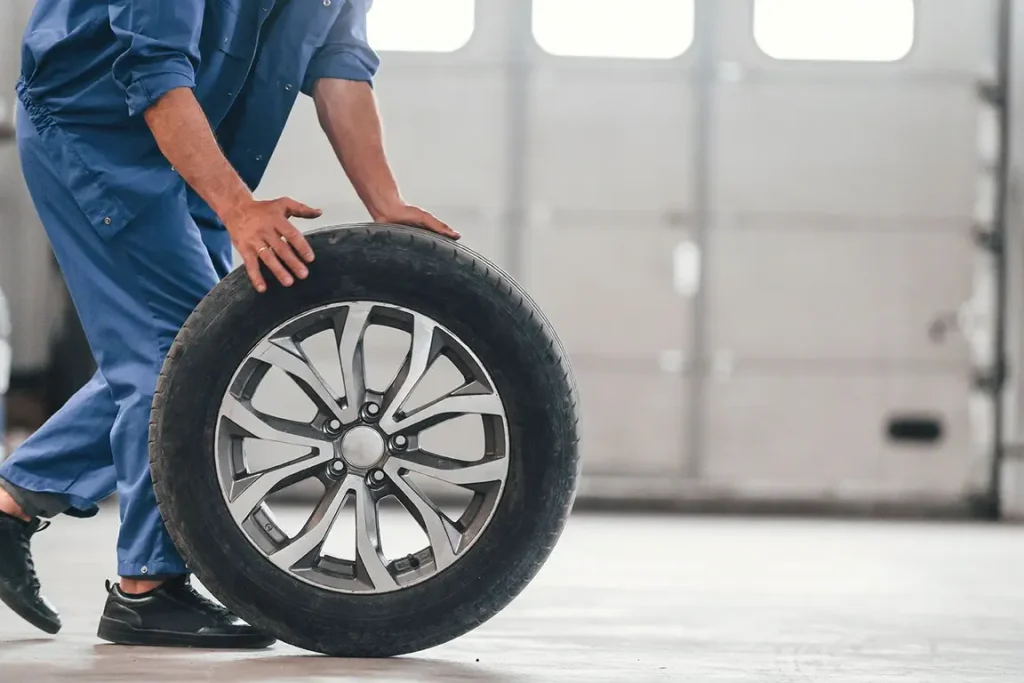 Mechanic rolling car tire in garage