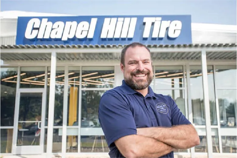 Smiling man stands outside Chapel Hill Tire shop