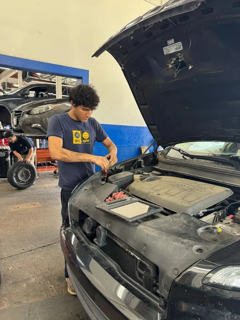 Mechanic working under raised hood at auto repair shop